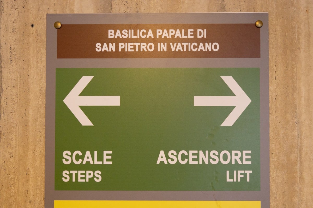 Panneau directionnel vert indiquant escaliers et ascenseur avec flèches blanches