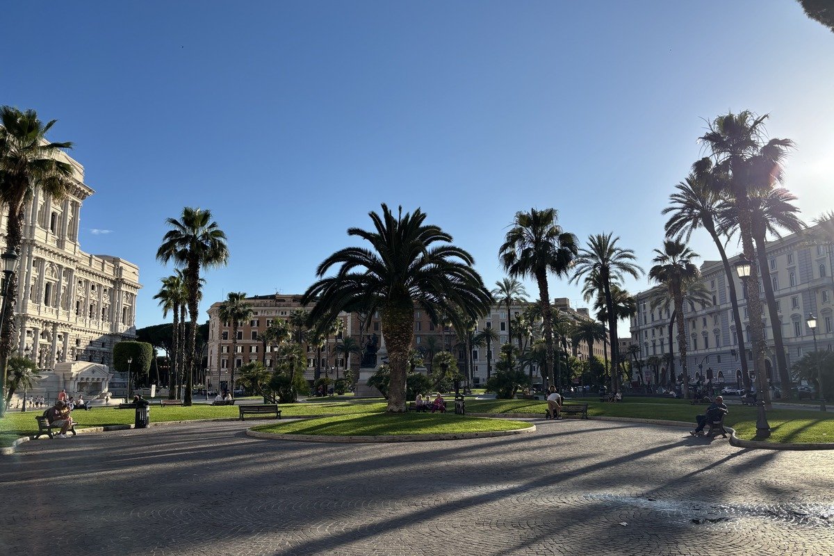 Place ensoleillée avec palmiers, pelouse verte et bâtiments classiques