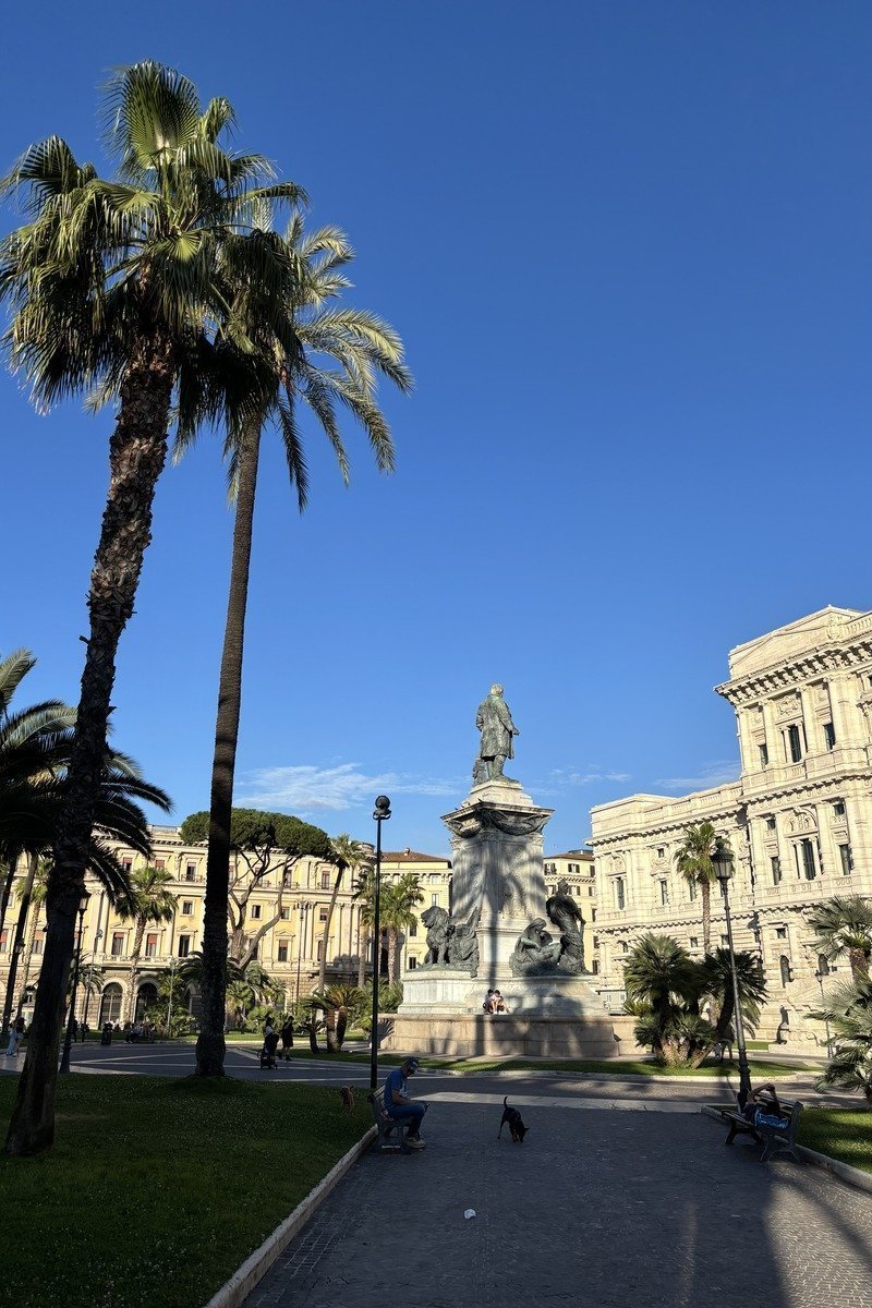 Place Cavour animée avec palmiers, statue sur piédestal et façade néoclassique