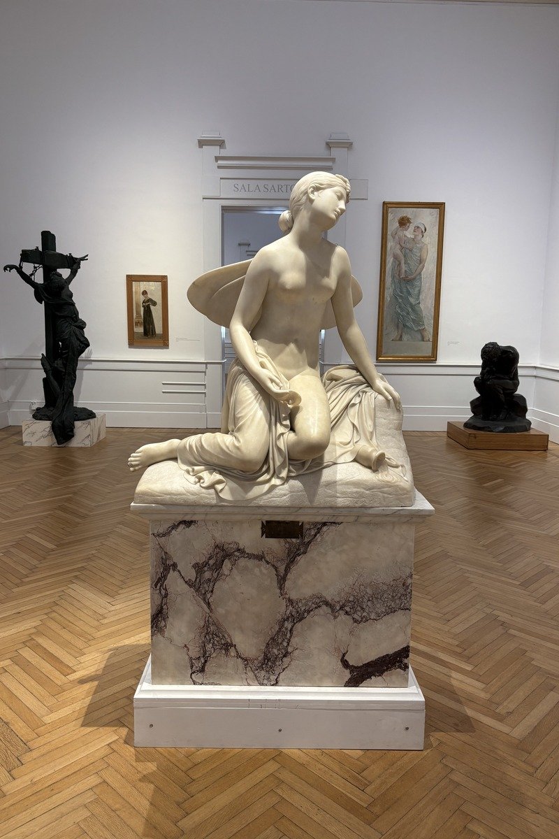 Statue en marbre blanc d'une femme assise dans une salle de musée