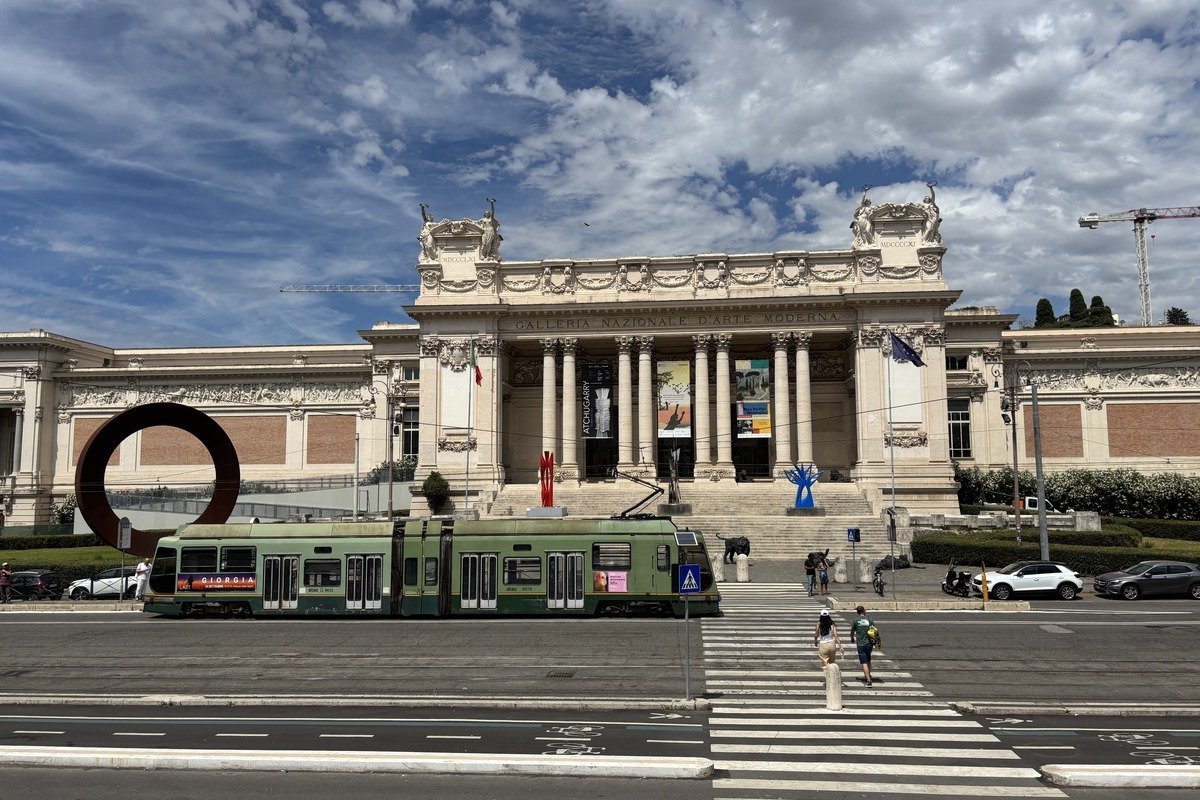 Tramway vert devant la façade d'un musée néoclassique sous ciel nuageux