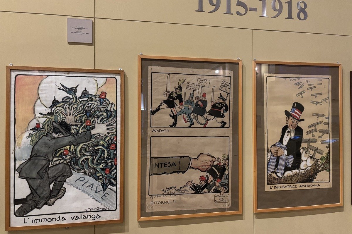 Trois affiches satiriques italiennes encadrées exposées sur un mur beige