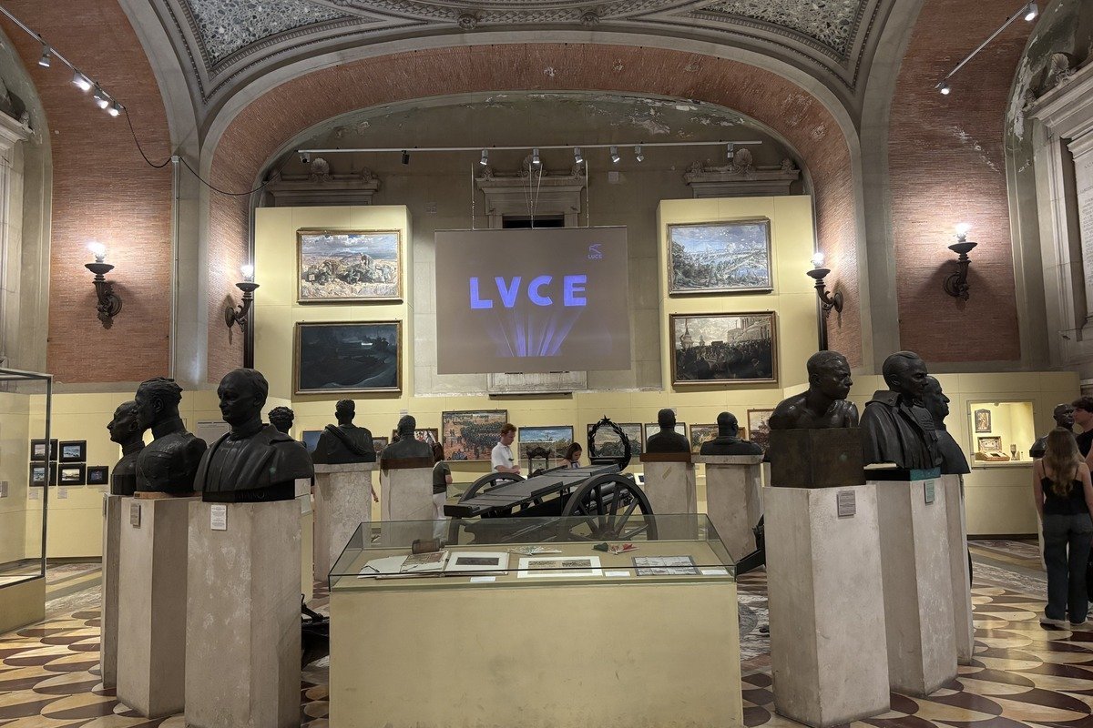 Grande salle de musée avec bustes en bronze et écran de projection